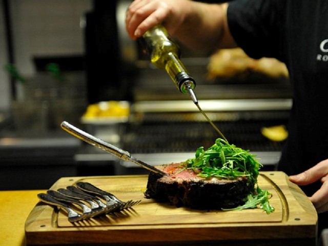 Chef preparing a steak at Charcut Roast House in Calgary | ''